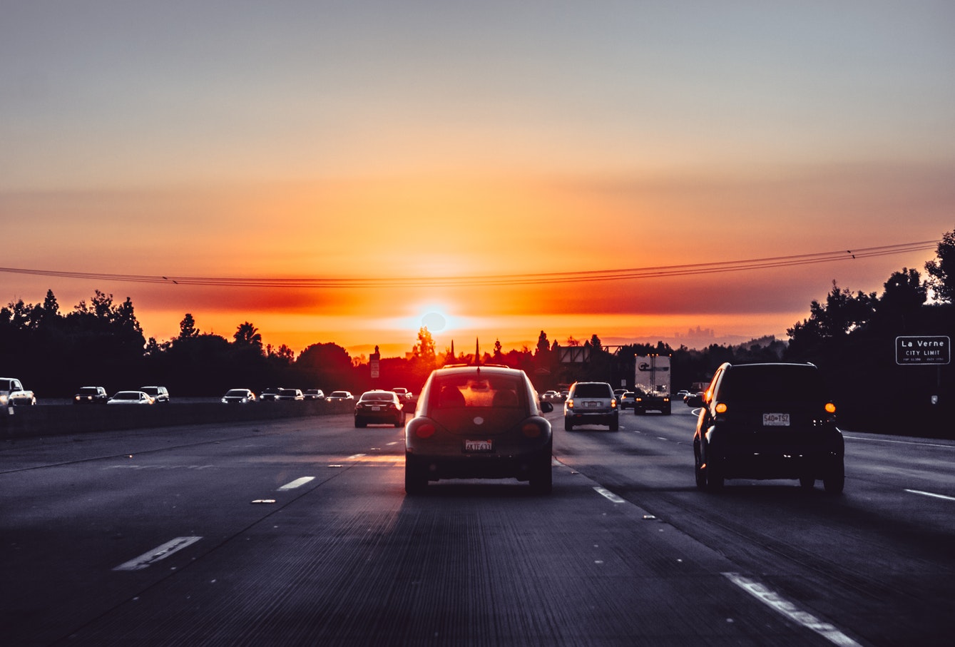 Cars driving on freeway at sunset